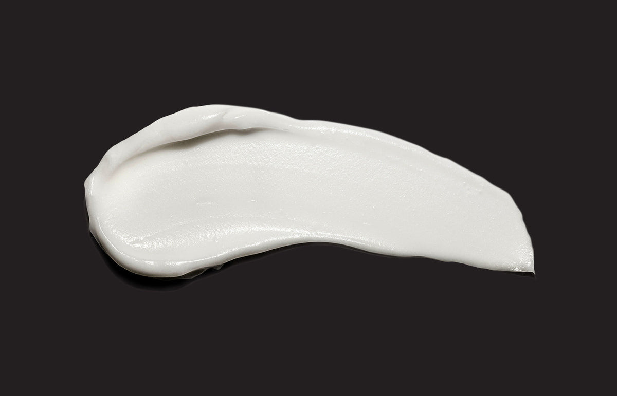 Swatch of white hand cream smeared across a black background