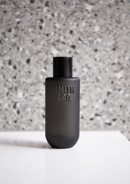 Black Smith and Co room spray on a white plinth against a terrazzo wall
