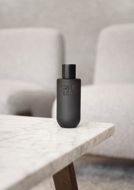 Black Smith and Co room spray on a marble bench with boucle chairs behind