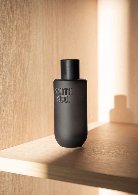 Black Smith and Co room spray on a pale timber shelf in warm light