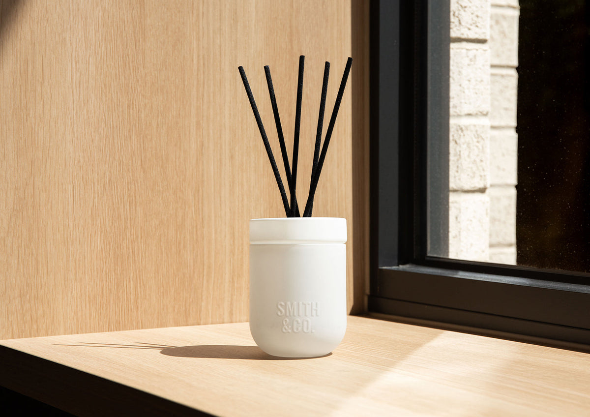 White Smith and Co diffuser casting a long shadow on a sunlit timber window ledge