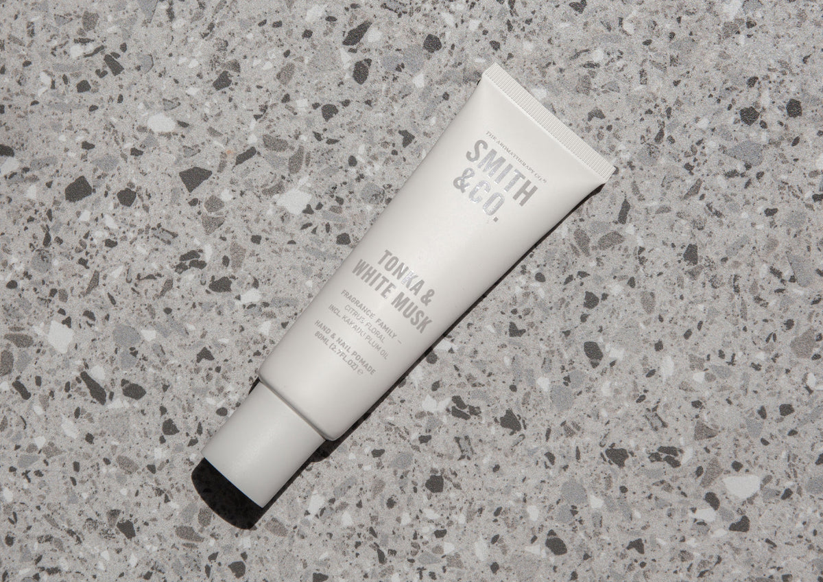 White hand cream tube lying flat on a grey terrazzo surface
