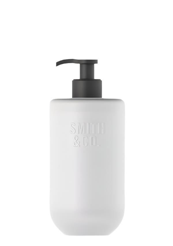 Frosted glass Smith and Co lotion bottle with a black pump on a plain background
