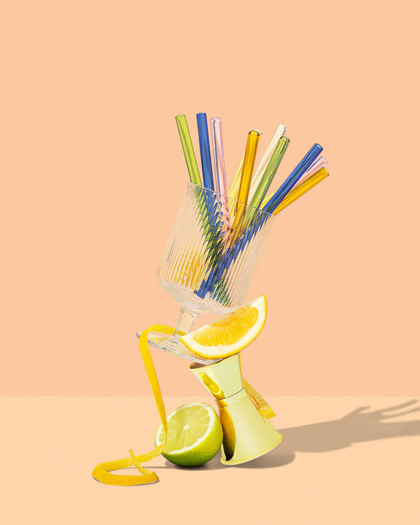 A sustainable Sucker glass filled with reusable Sucker cocktail straws and a slice of lemon.