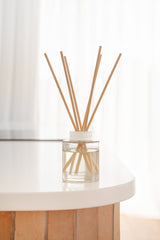 Clear glass diffuser with wooden sticks on a white surface