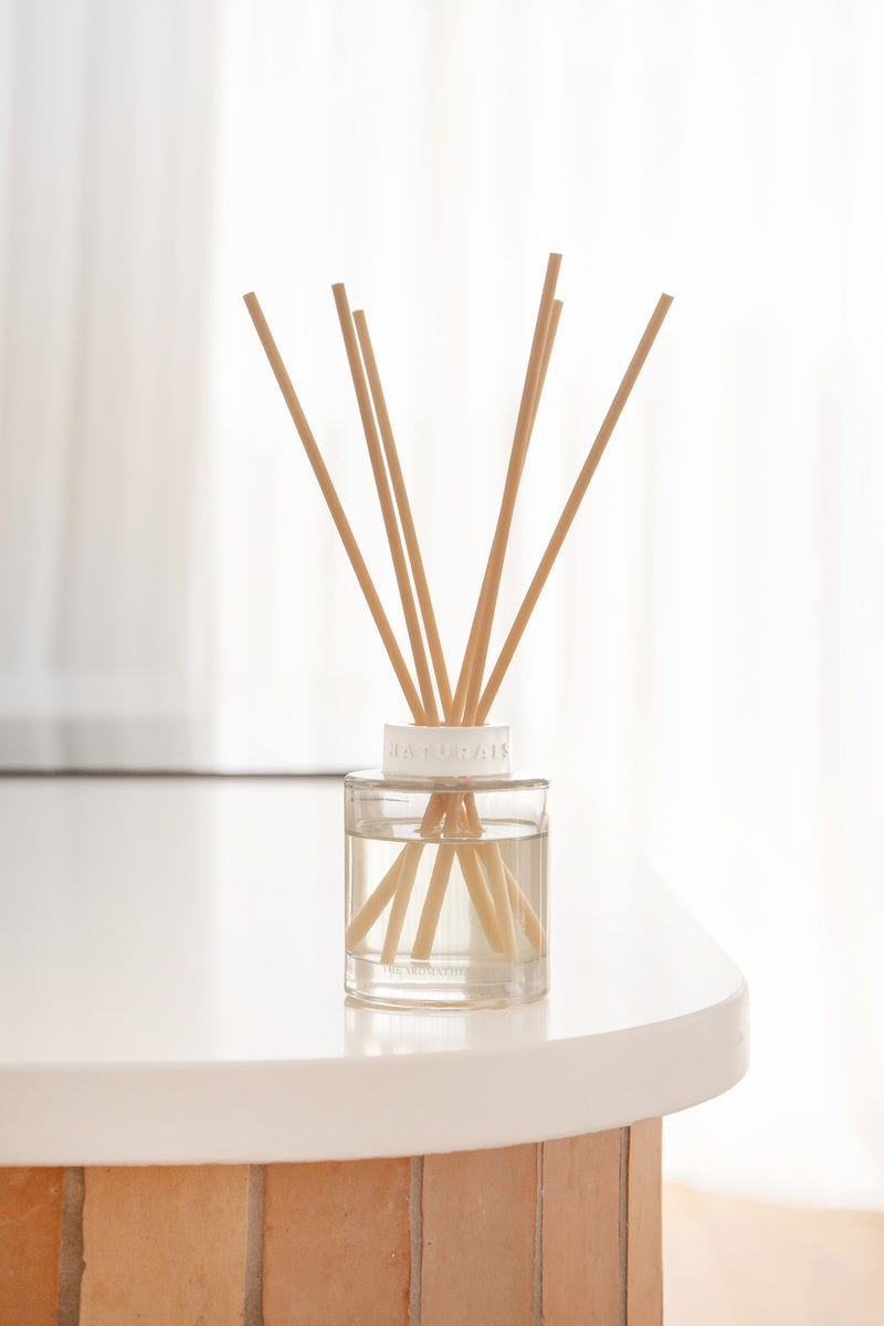 Clear glass diffuser with wooden sticks on a white surface