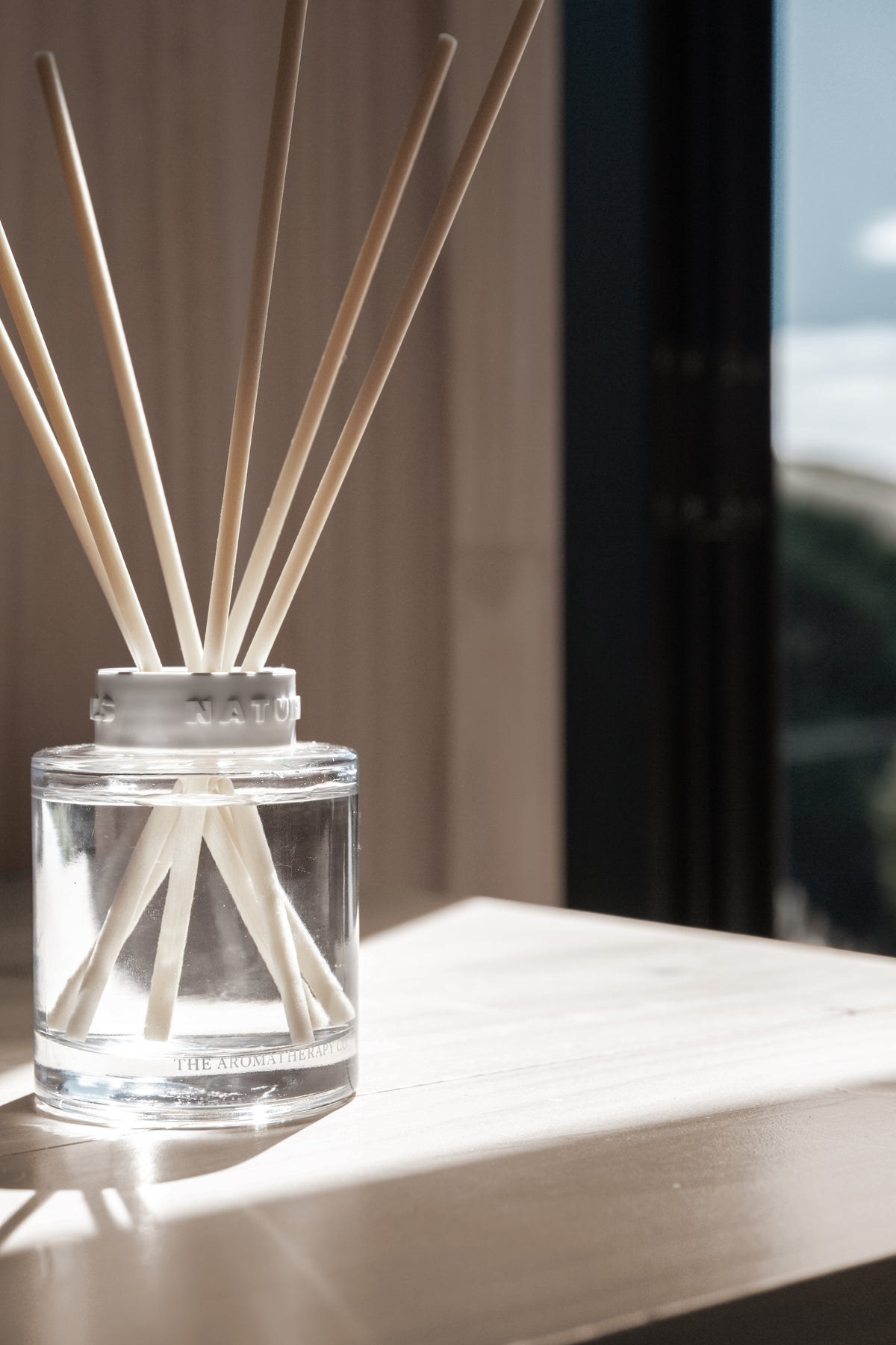 Naturals diffuser on a pale timber ledge beside a dark window frame