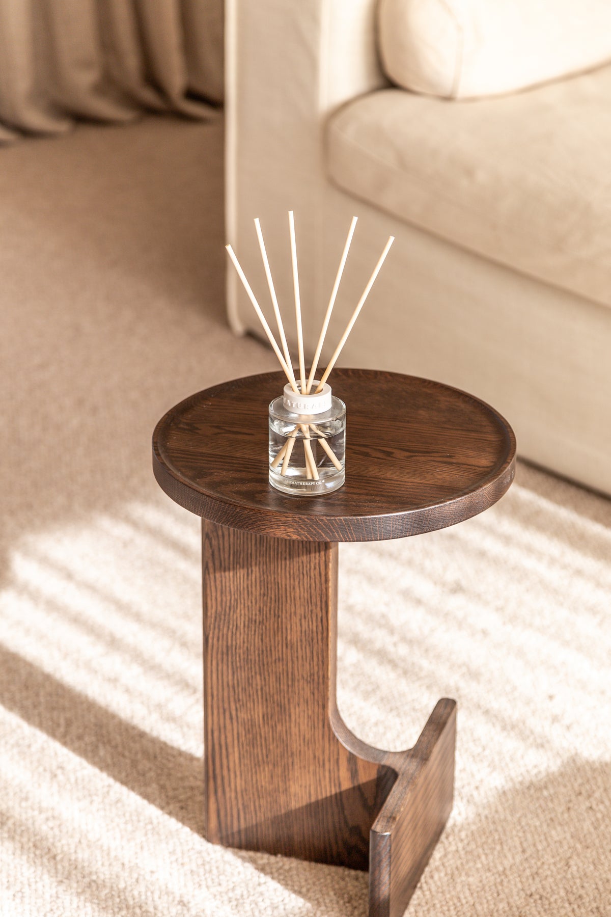 Naturals diffuser on a dark sculptural side table standing on a striped rug