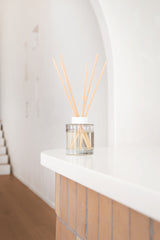 Clear diffuser with wooden sticks on a white surface