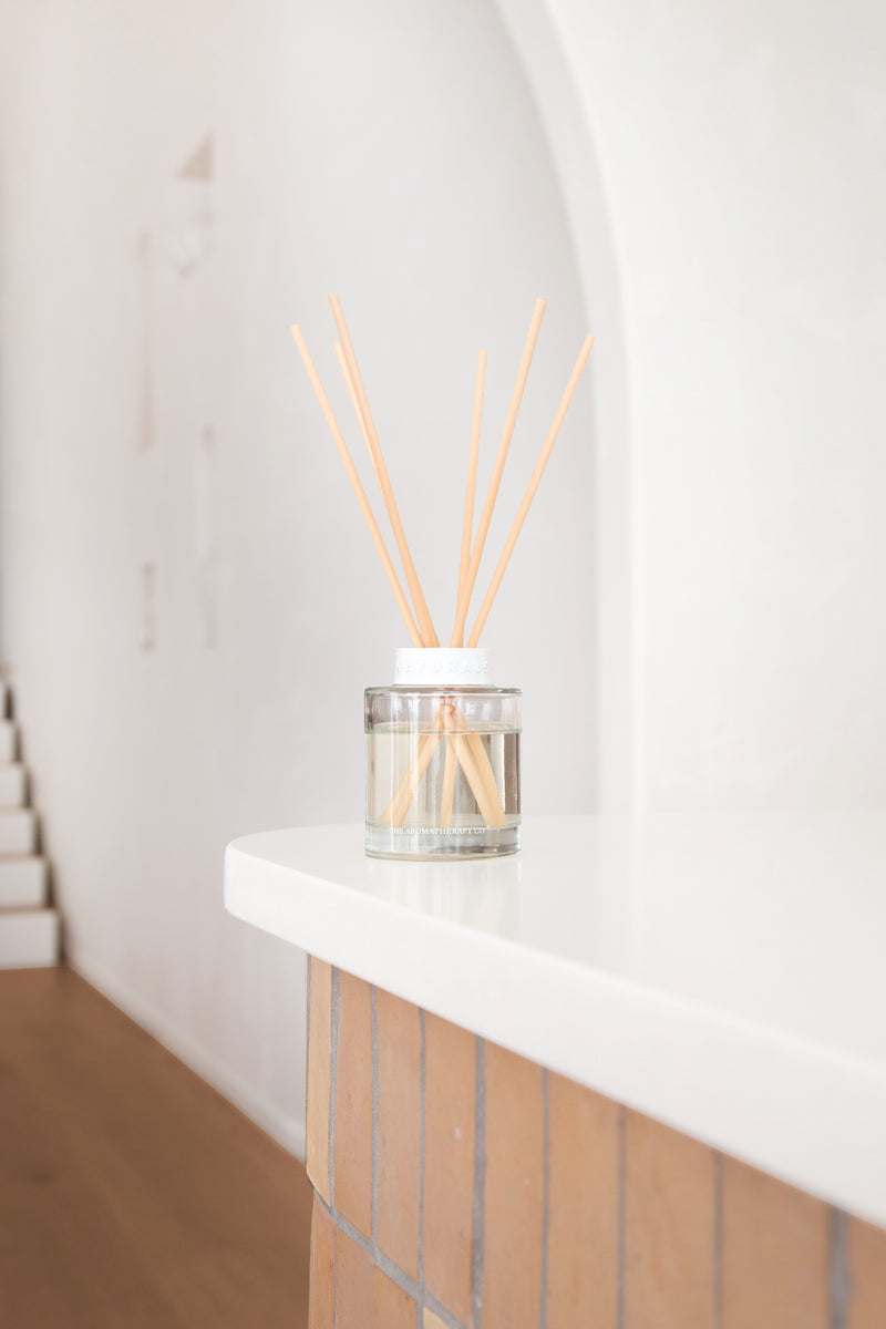 Clear diffuser with wooden sticks on a white surface