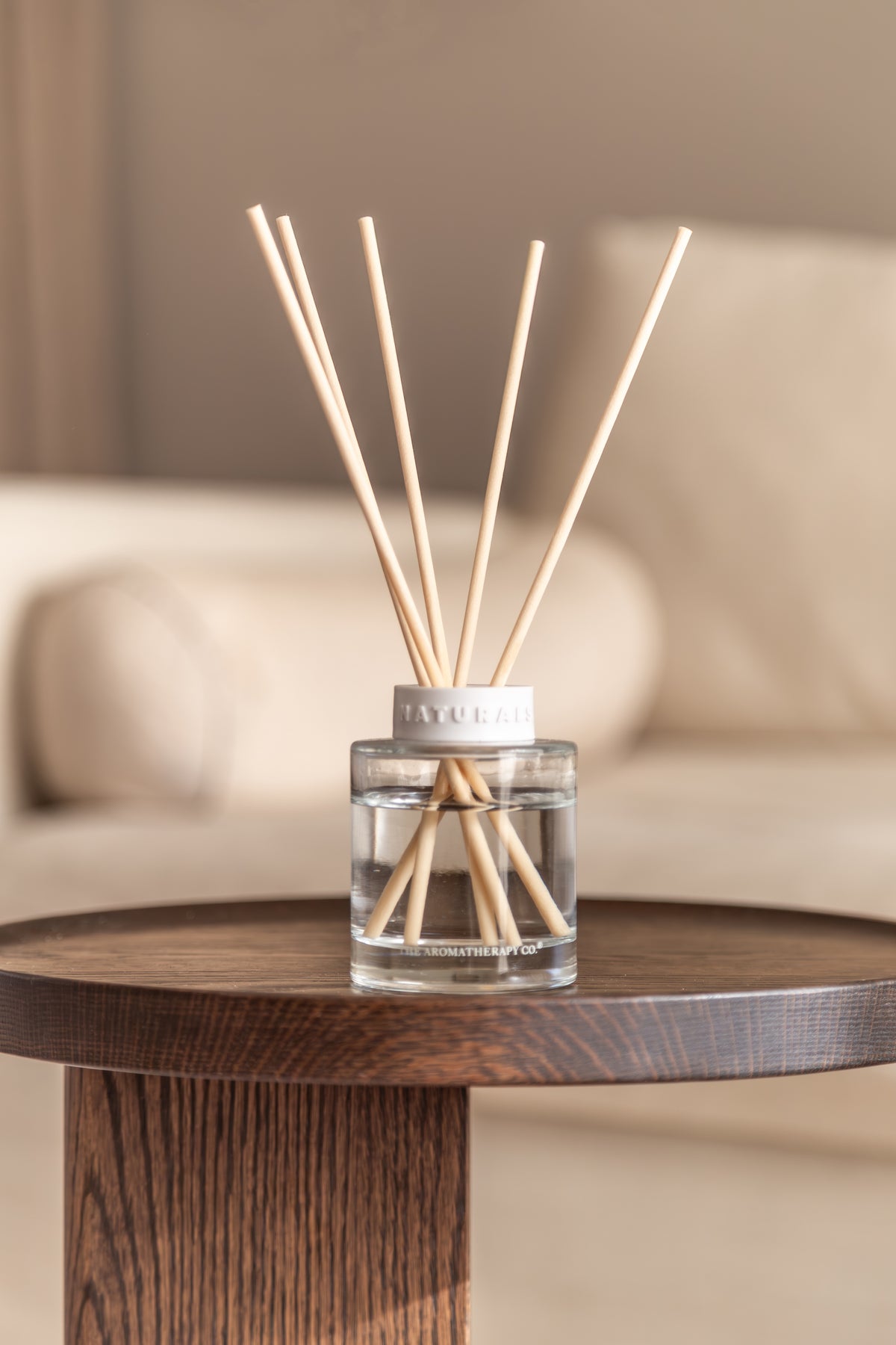 Naturals diffuser on a dark timber pedestal table with a cream sofa behind