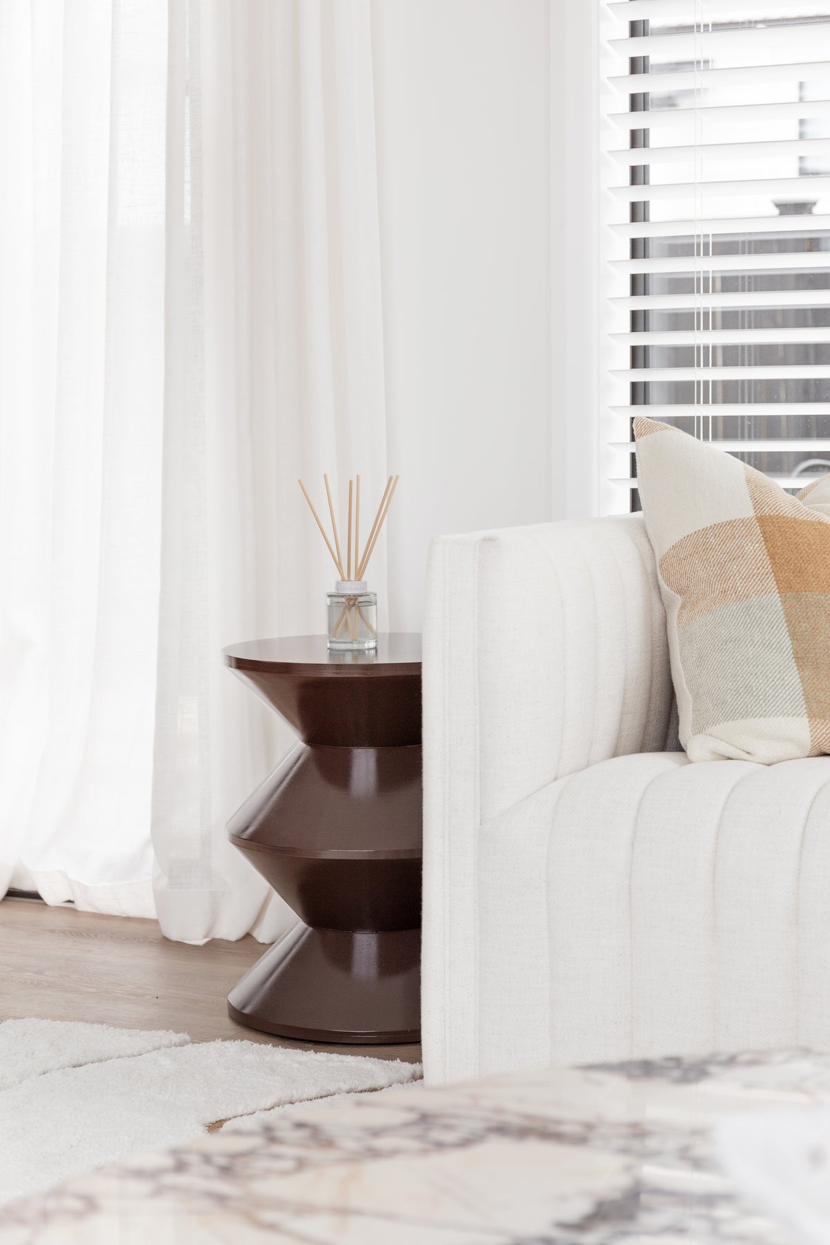 Naturals diffuser on a dark sculptural side table beside a fluted sofa and cushion