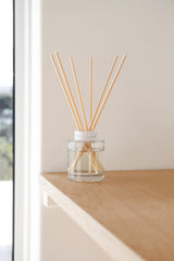 Diffuser with wooden sticks on a wooden surface near a window