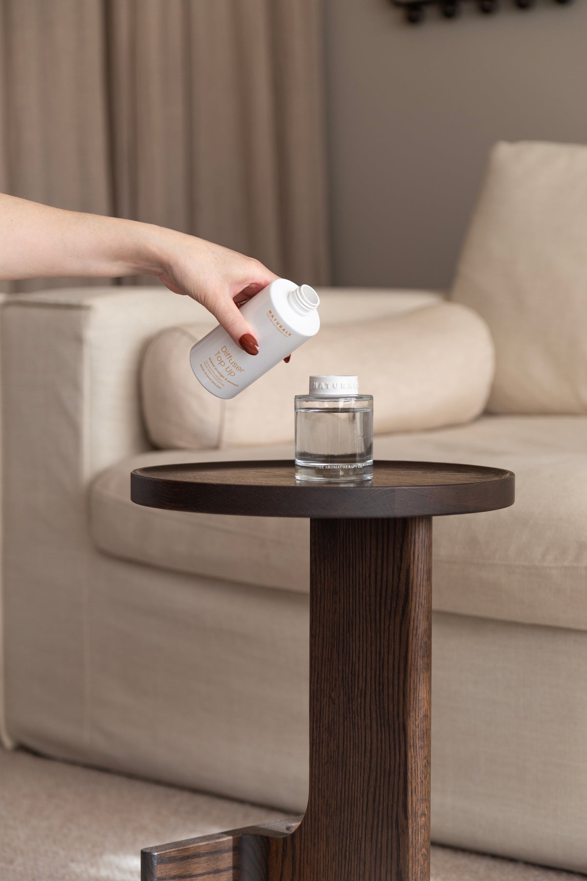 Hand tipping the refill bottle over the empty Naturals diffuser bottle