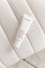 Tube of Santal & Vanilla Orchid hand cream resting on a curved boucle-textured seat cushion, styled in soft, neutral tones for a calm, self-care aesthetic.