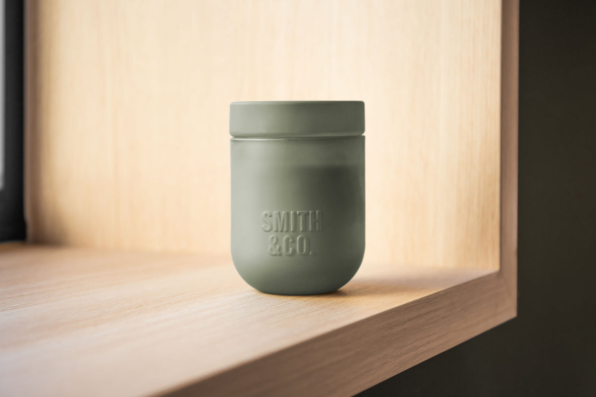 Smith and Co candle with its lid on, in a warmly lit timber niche
