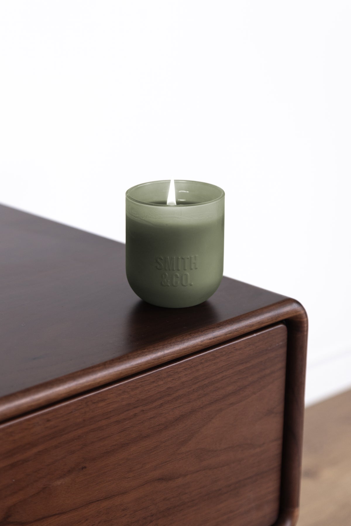 Close view of the Smith and Co candle with smoke curling from the wick
