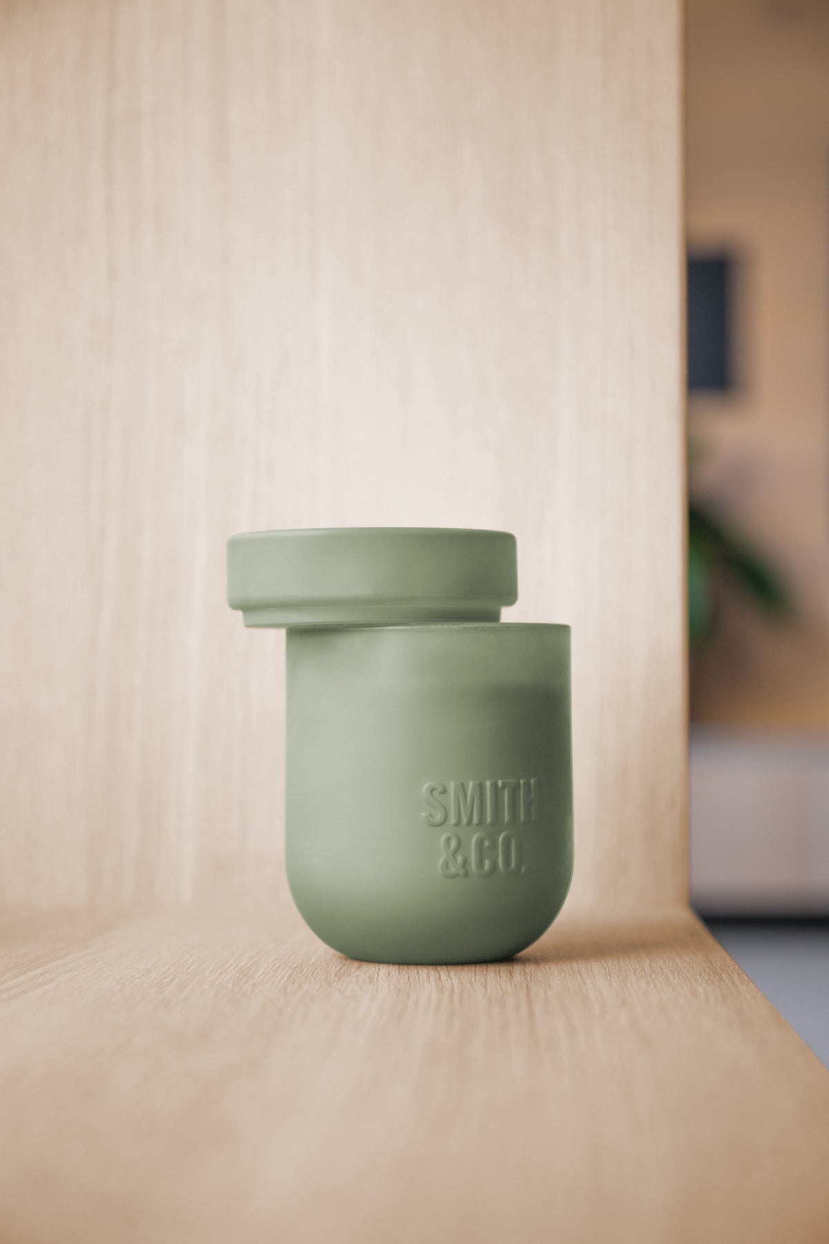 Smith and Co candle with its lid resting on top, on a pale timber shelf