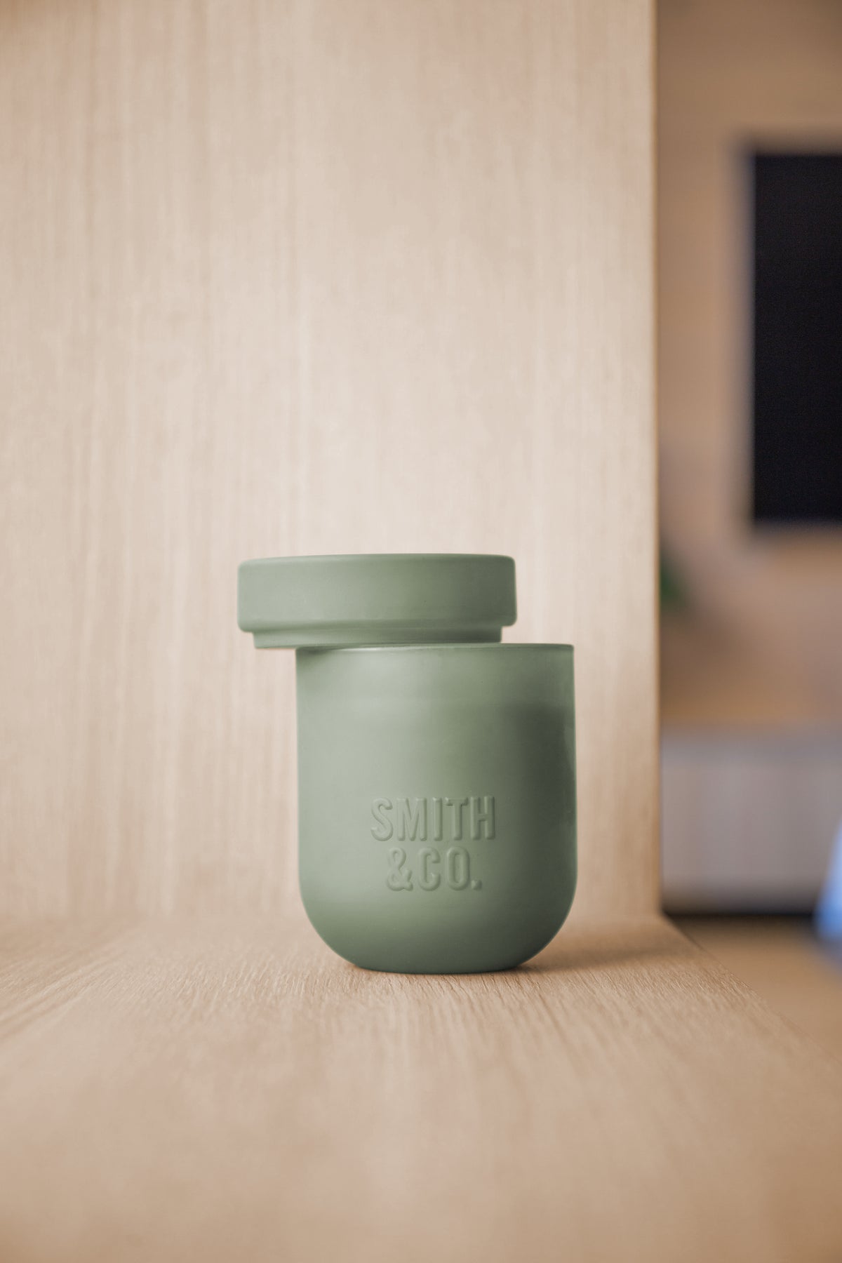 Smith and Co candle with its lid on, on a pale timber shelf in a living room