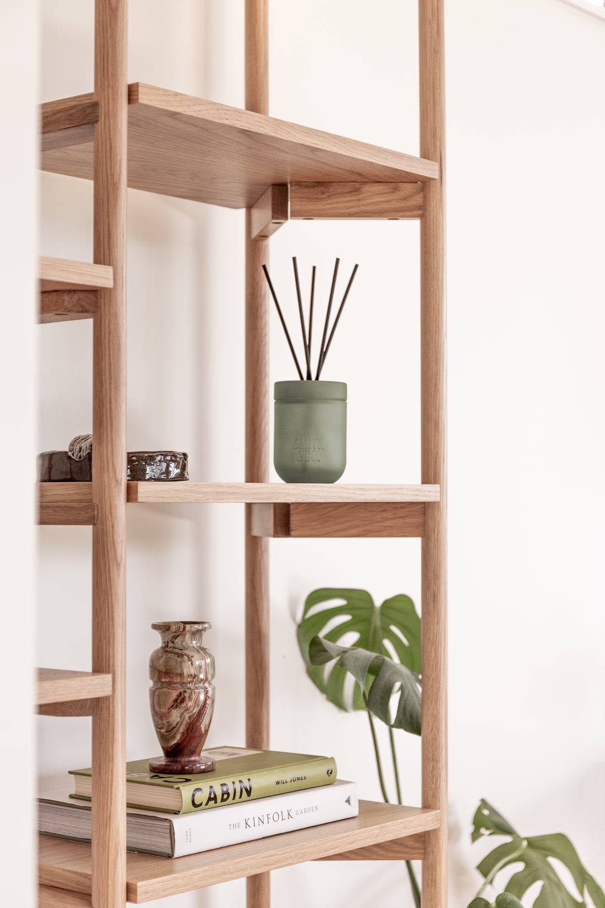 Smith and Co reed diffuser on an oak shelving unit with a patterned vase and books below