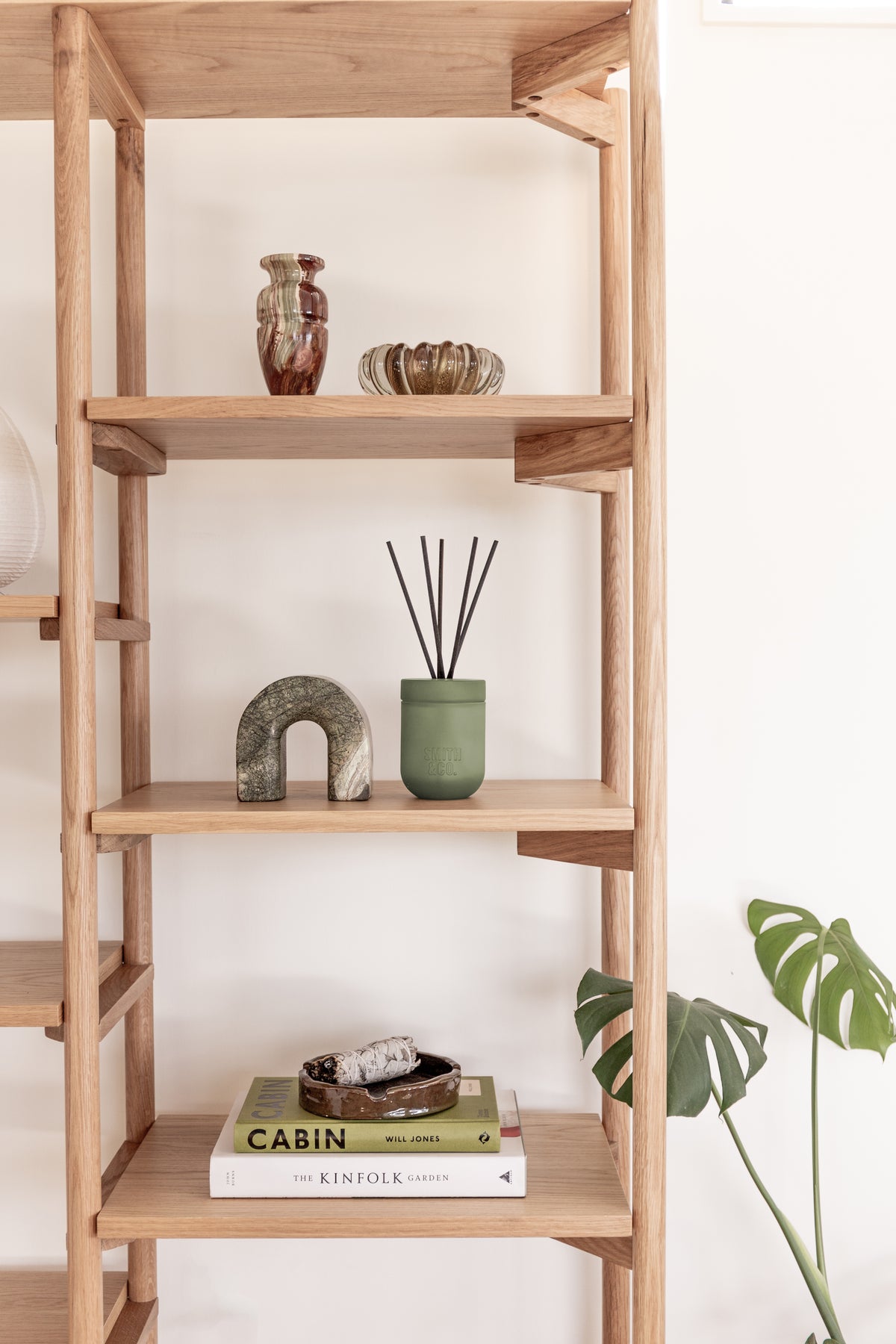 Oak shelving unit styled with the Smith and Co diffuser, a stone arch, a vase and stacked books
