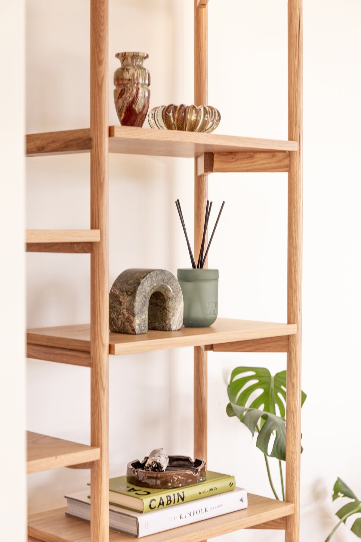 Angled view of oak shelving holding the Smith and Co diffuser, a stone arch and a patterned vase