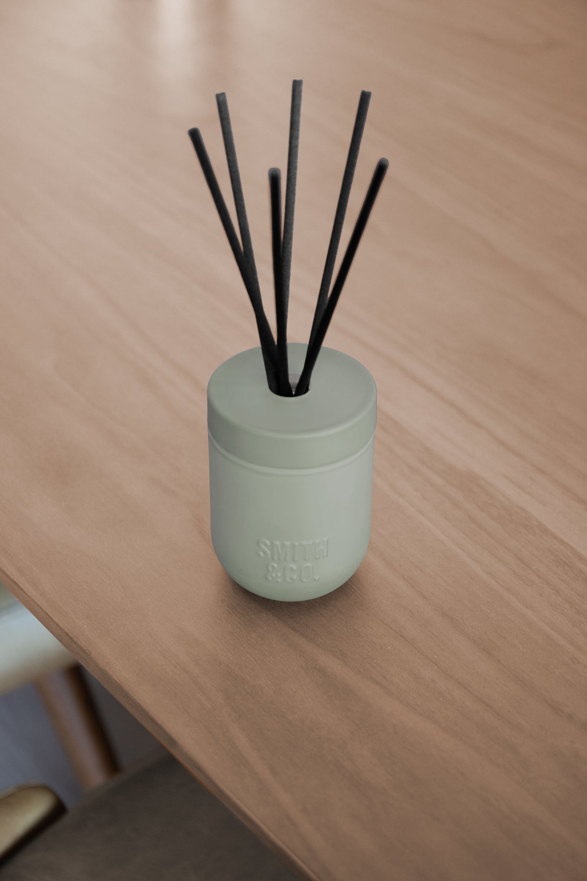 Smith and Co reed diffuser on the edge of a pale timber table, seen from above