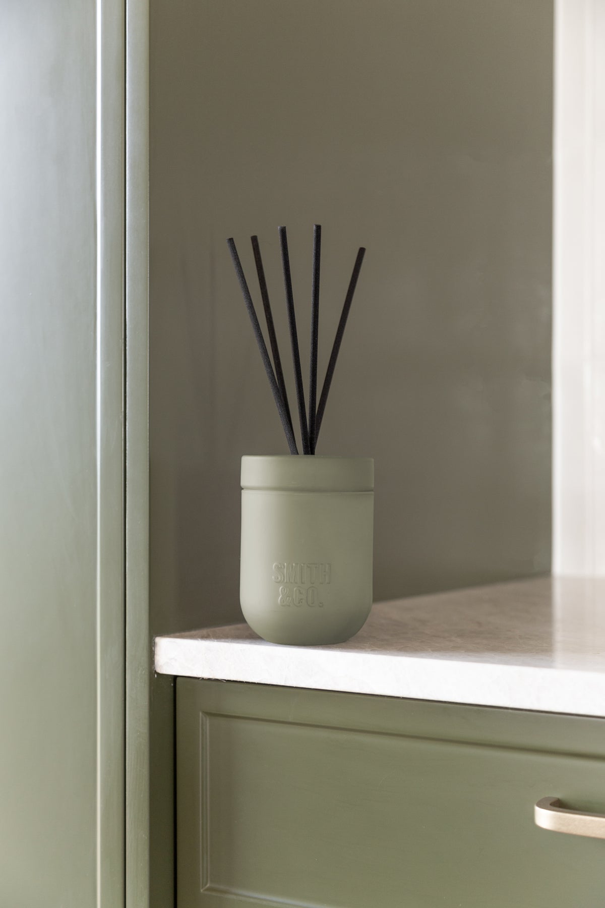 Smith and Co reed diffuser on a white benchtop above sage green cabinetry