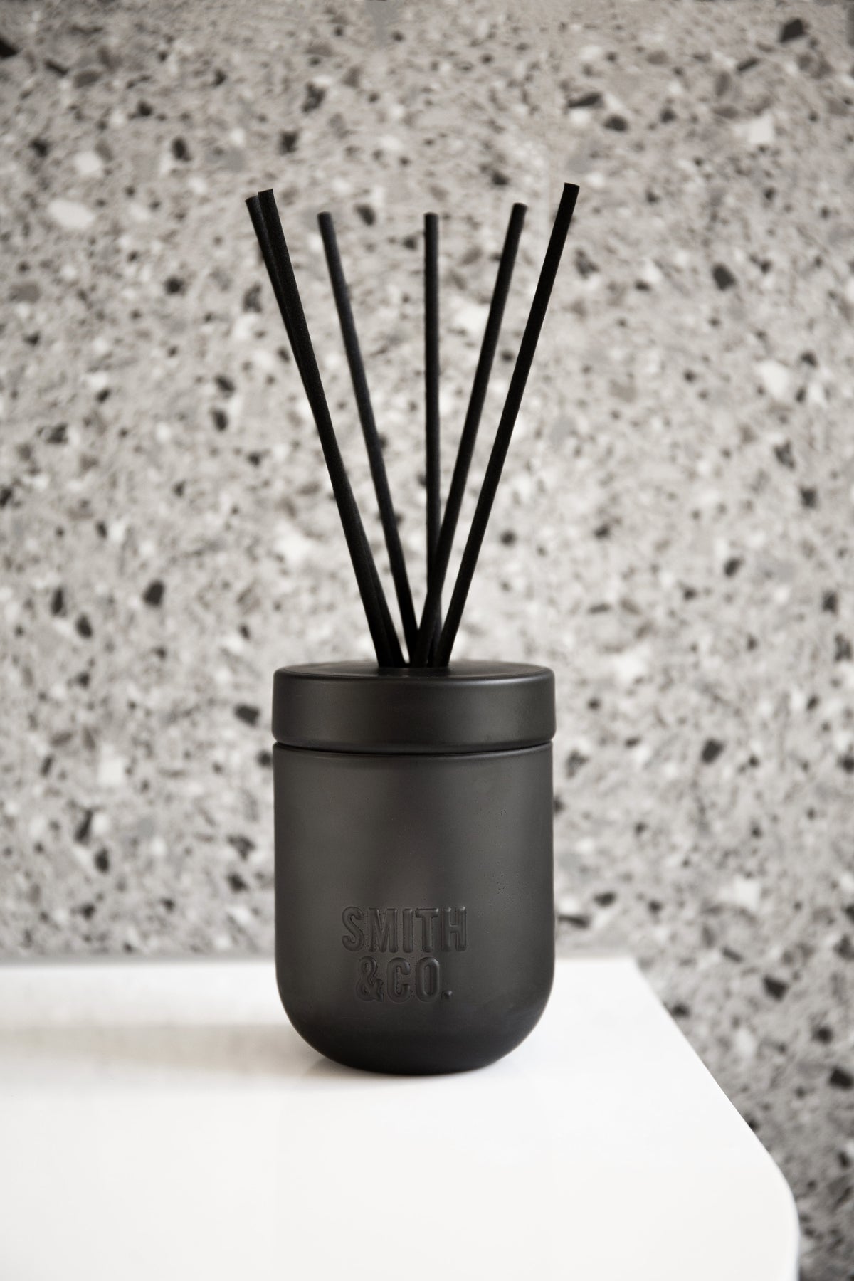 Smith & Co. diffuser on a white surface against a speckled terrazzo wall
