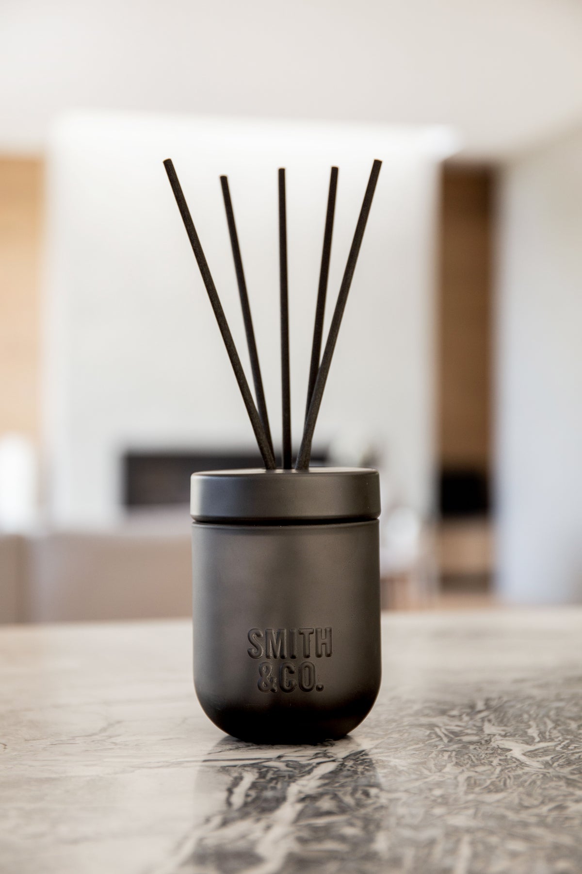 Smith & Co. diffuser on a marble bench with a living space softly blurred behind