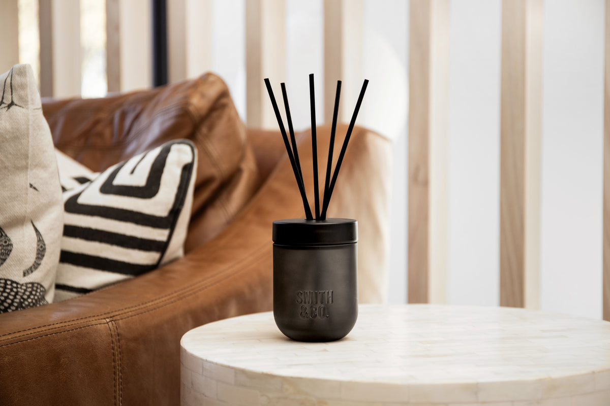 Smith & Co. diffuser on a white side table in front of a leather sofa with cushions