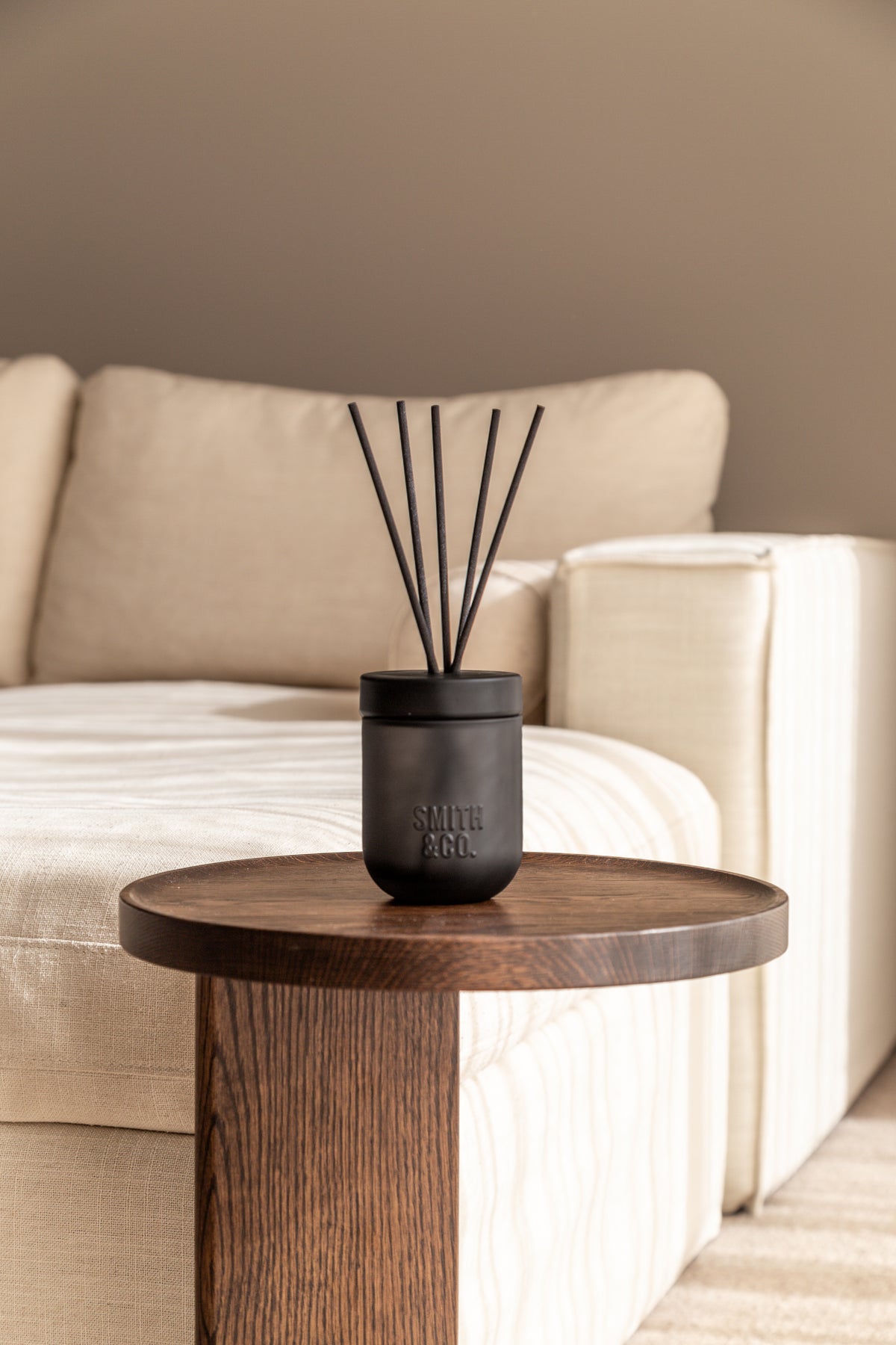 Smith & Co. diffuser on a round timber side table beside a cream sofa