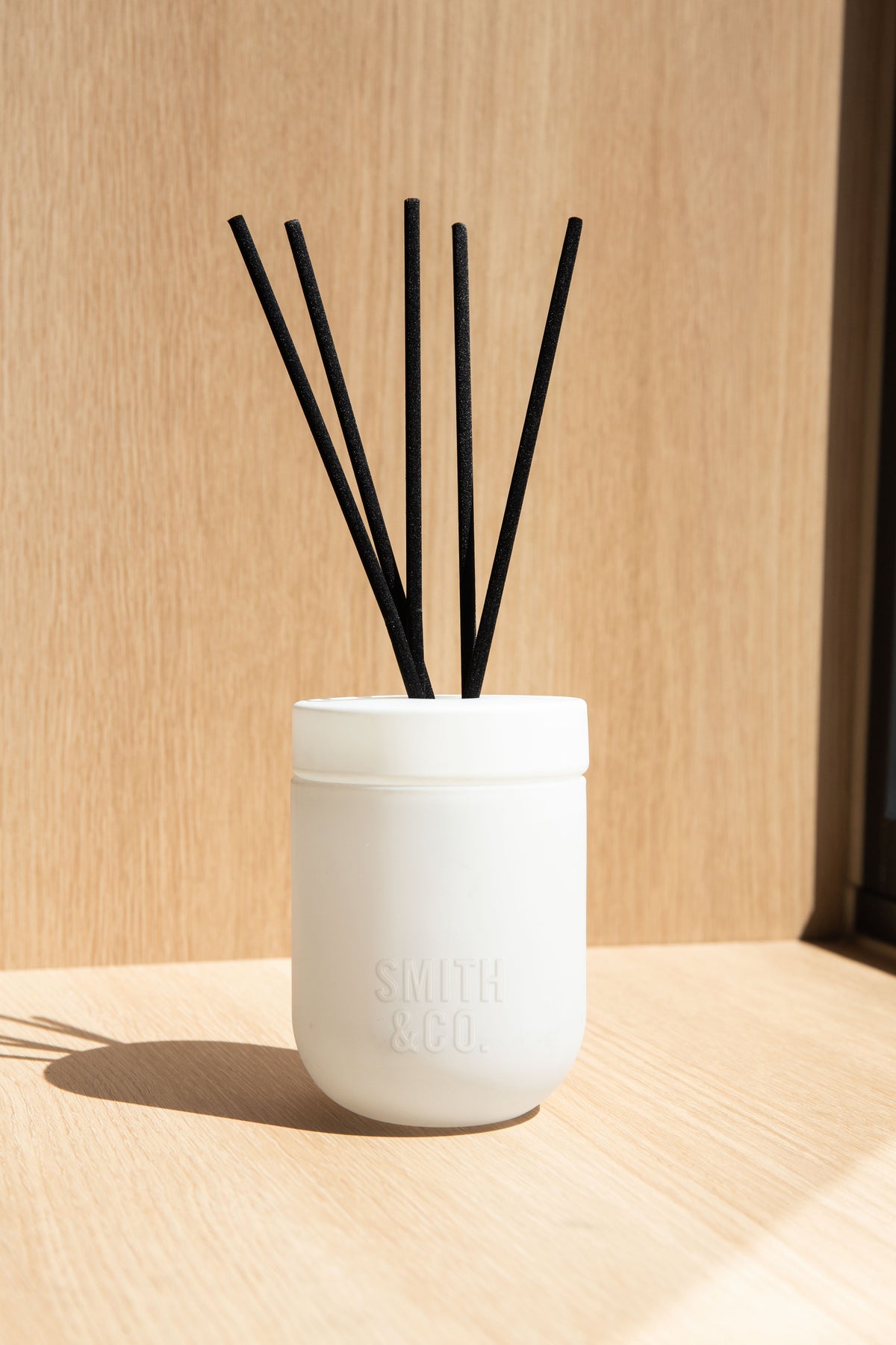 White Smith and Co diffuser in strong sunlight on a pale timber ledge