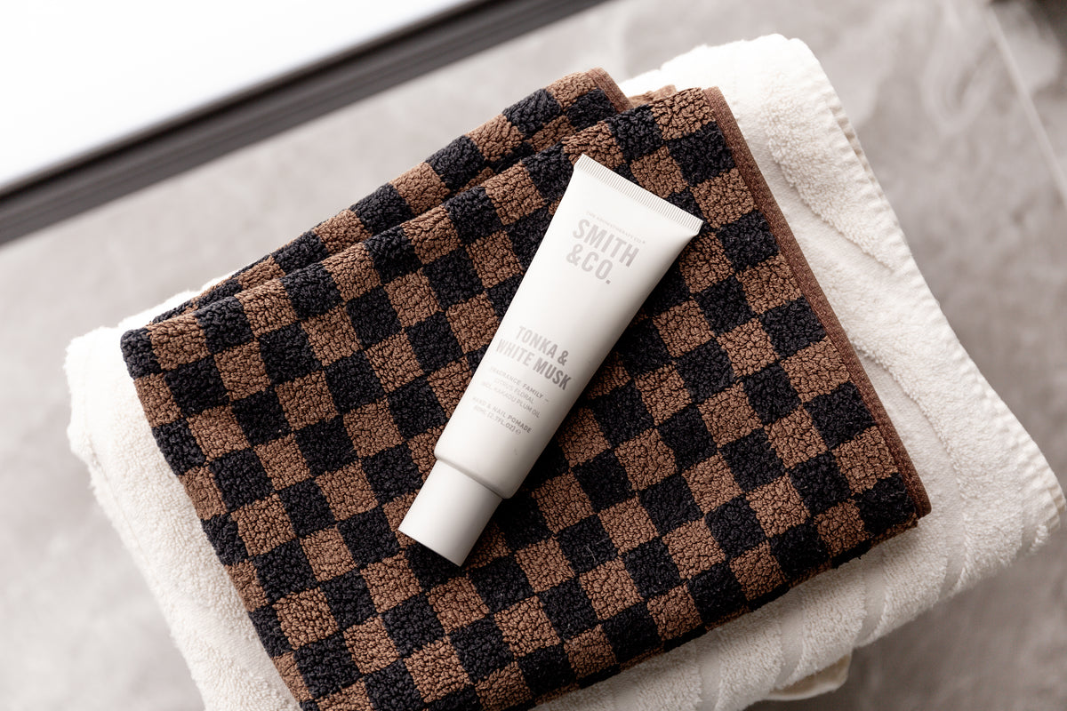 Hand cream tube on folded checkerboard and white towels