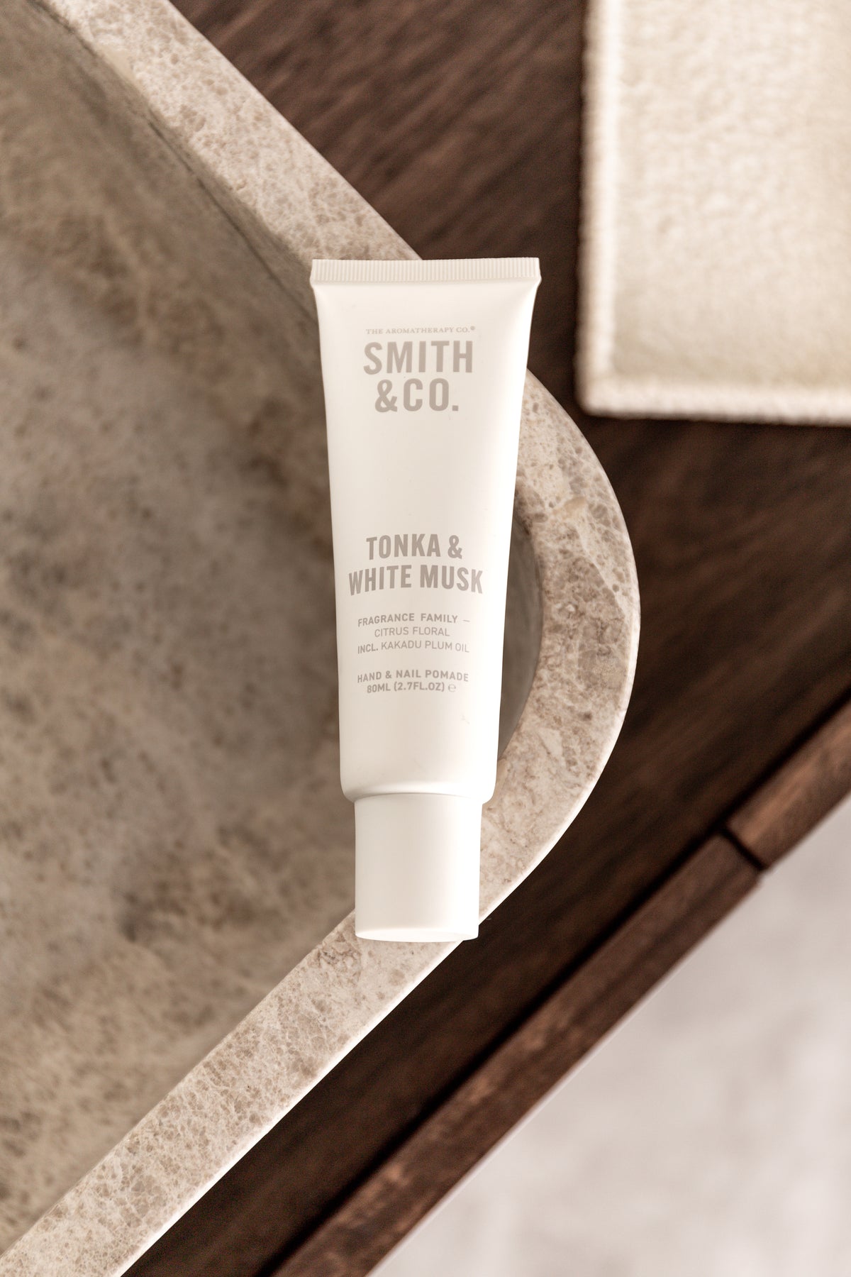 Hand cream tube on a stone ledge with a textured mat behind