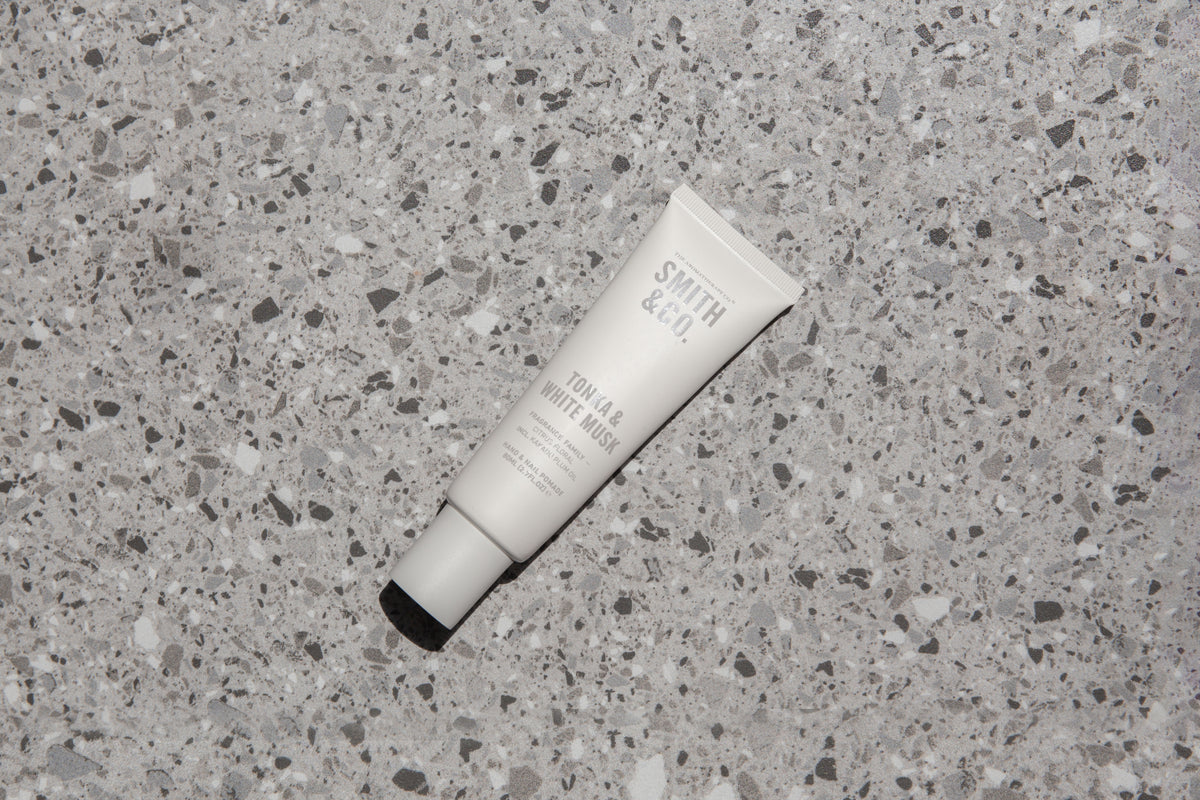 White hand cream tube laid on a pale grey terrazzo benchtop