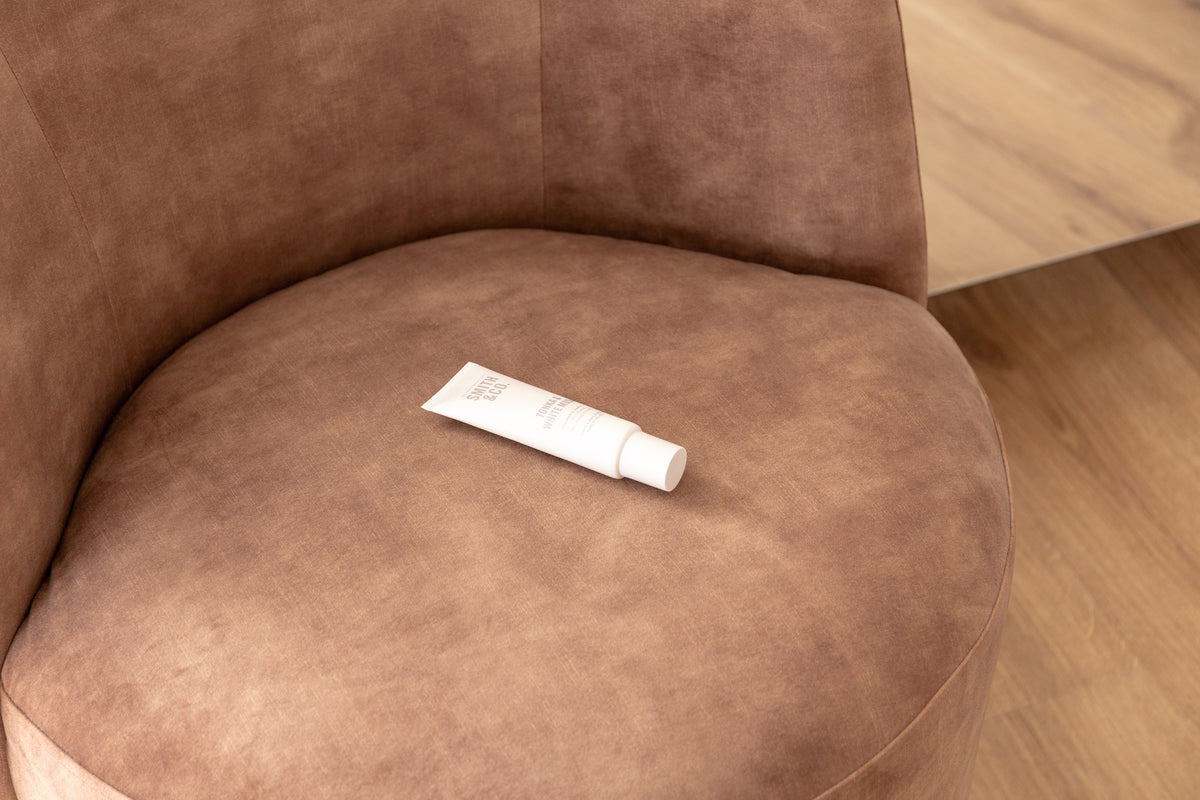 Hand cream tube resting on the seat of a brown suede armchair