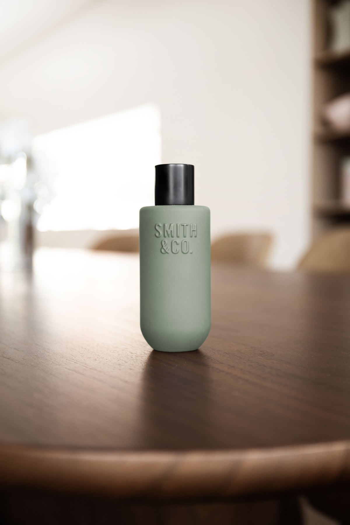 Smith & Co. room spray on a dark walnut table with a bright living room blurred behind