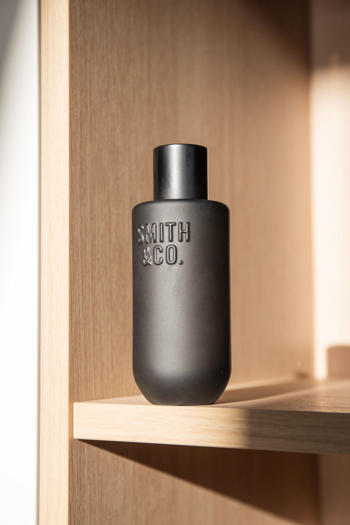 Black Smith and Co room spray on a pale timber shelf in daylight