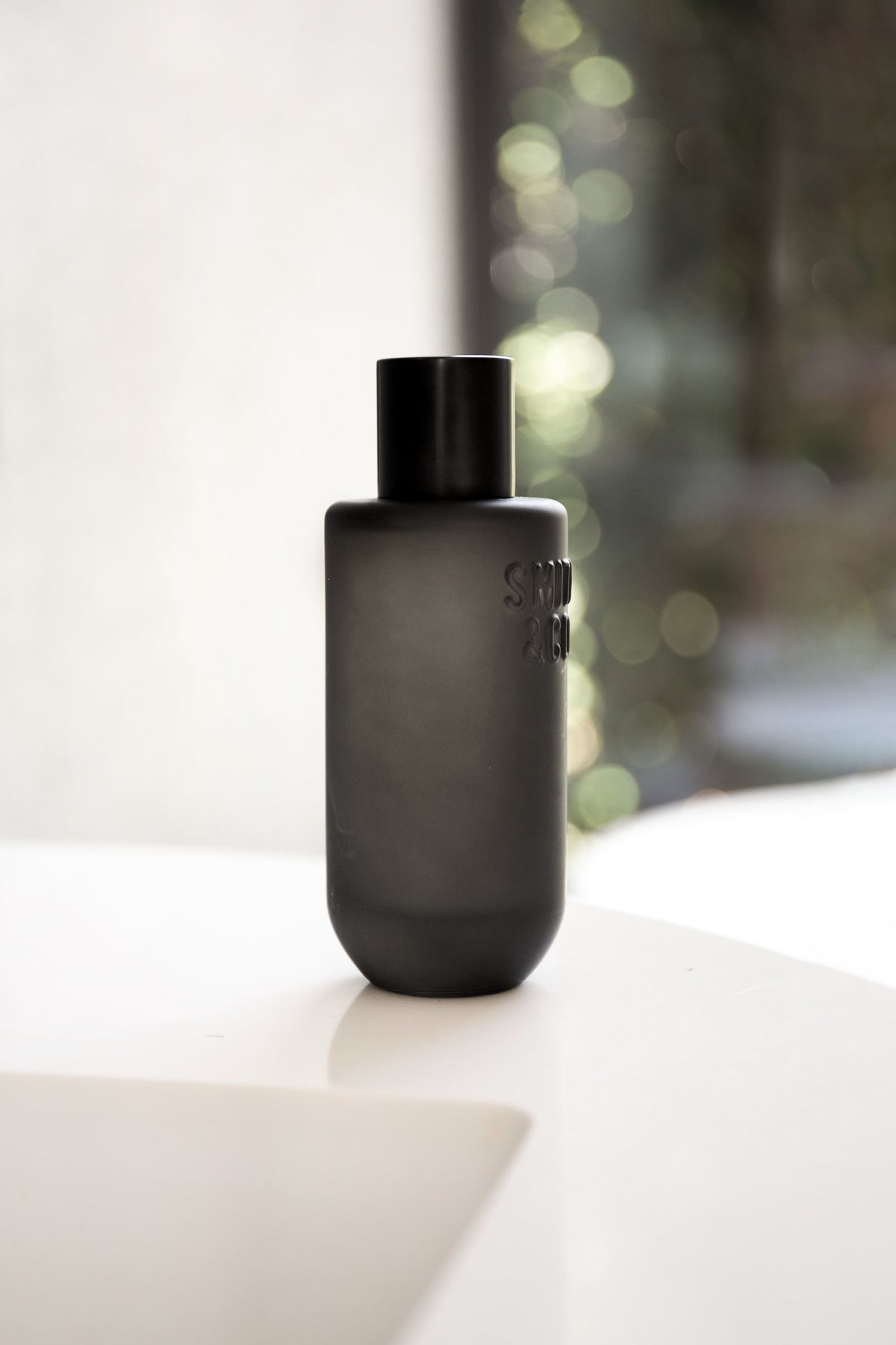 Black Smith and Co room spray on a white surface with green garden bokeh behind