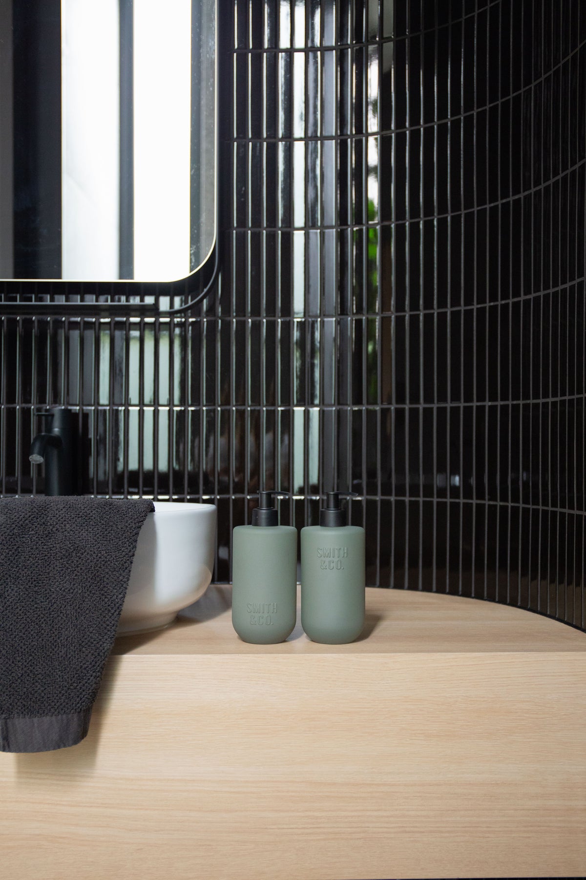Sage green Smith & Co. bottles against glossy dark tiles