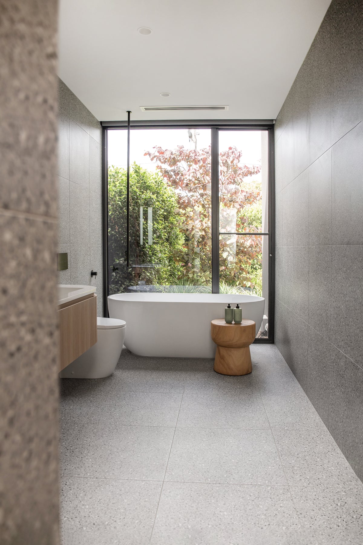 Bathroom looking towards a window, with Smith & Co. bottles on a stool