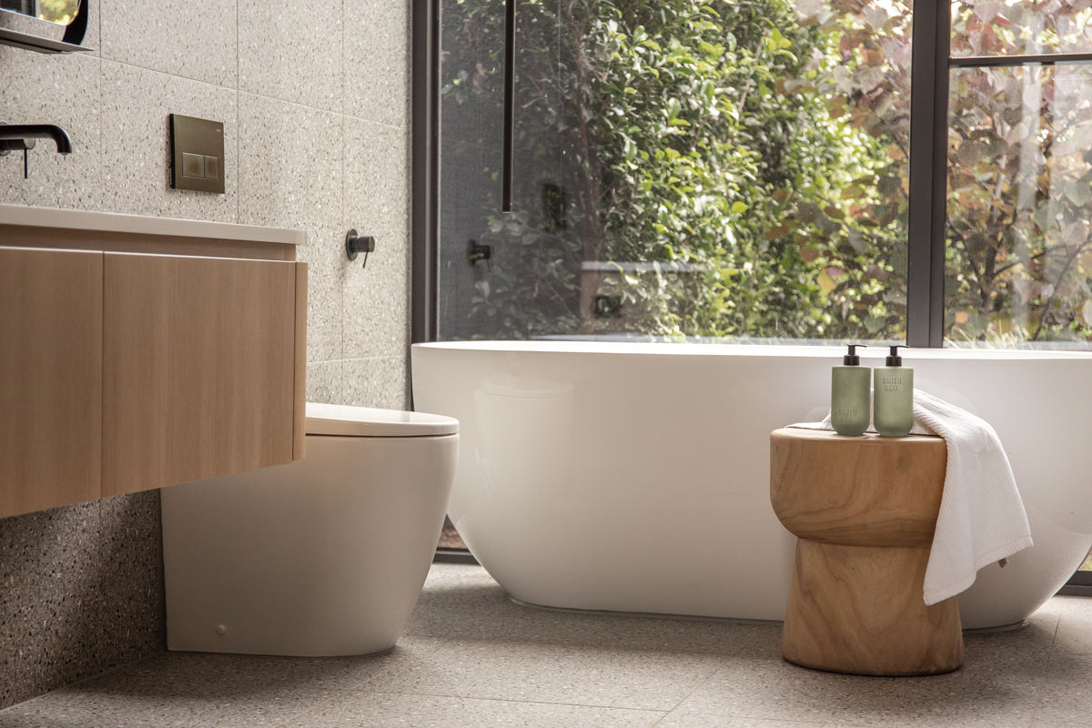Bathroom with a freestanding bath and a timber stool holding Smith & Co. bottles
