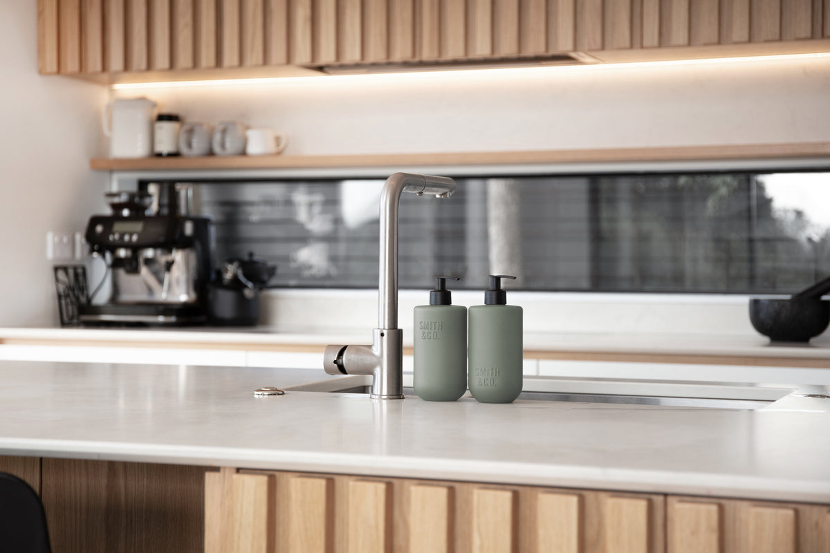 Kitchen with timber cabinetry and Smith & Co. bottles on the white benchtop