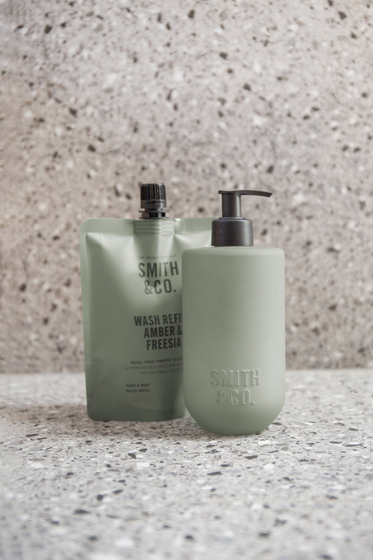 Sage green Smith & Co. bottle and refill against a terrazzo wall