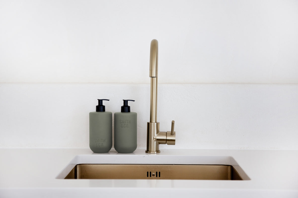 Brass tap over a white sink with Smith & Co. bottles alongside