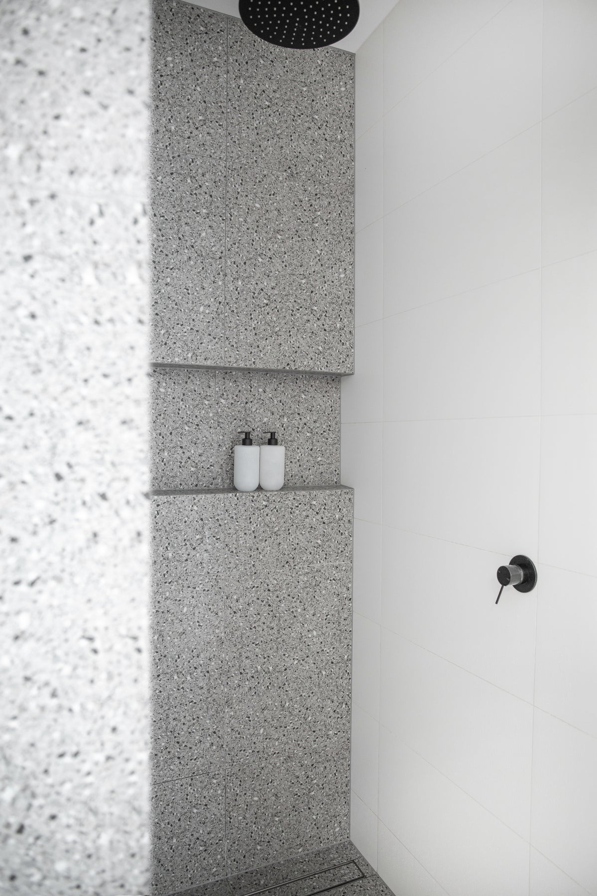 Terrazzo bathroom with Smith and Co bottles on a ledge beside the shower