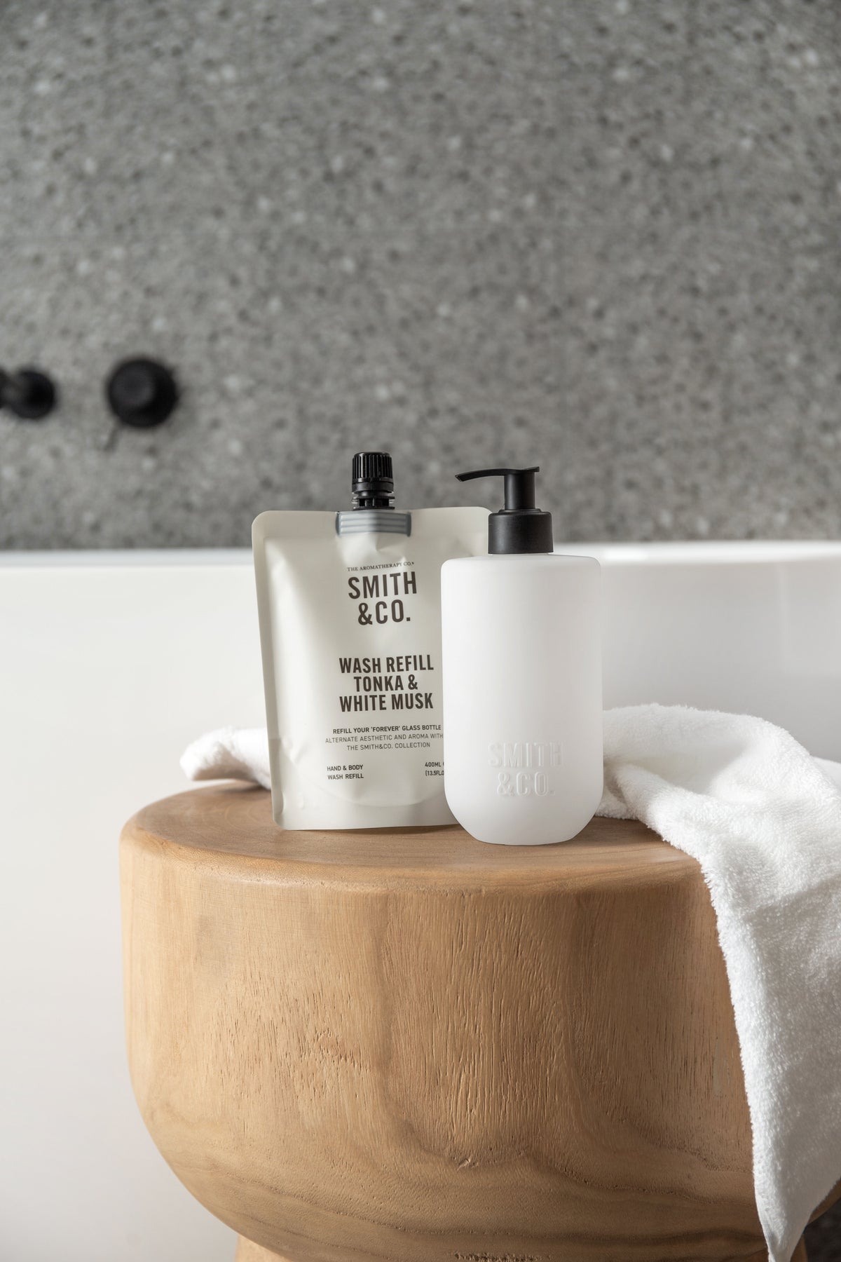 Smith and Co lotion and wash on a round timber riser with a white towel