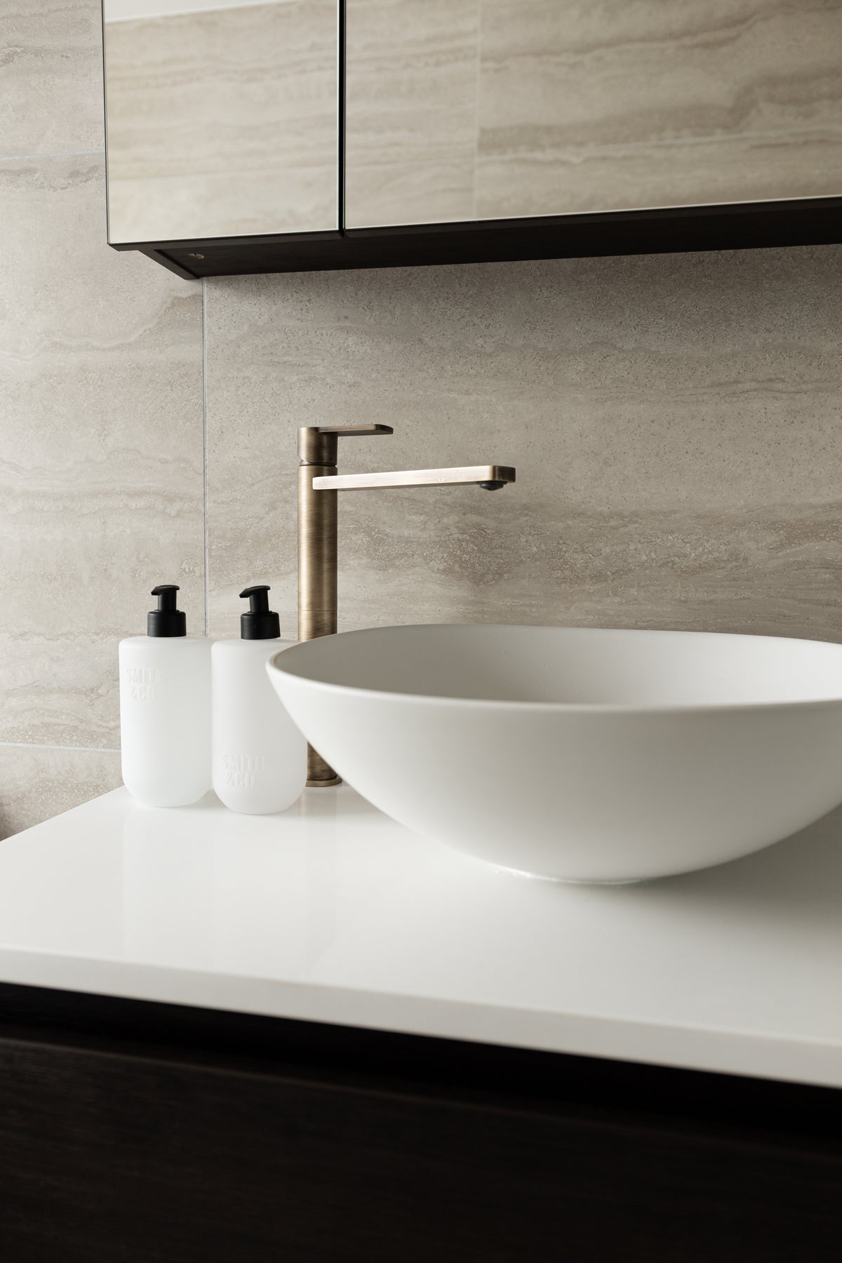Vanity with a white vessel basin, brass tap and Smith and Co bottles