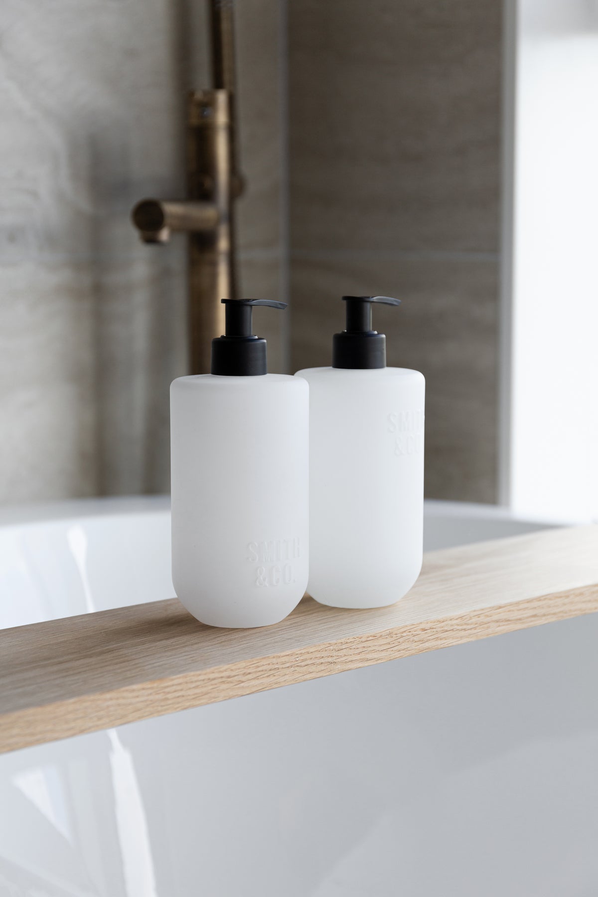 Smith and Co bottles on a timber ledge beside a bath with a brass tap